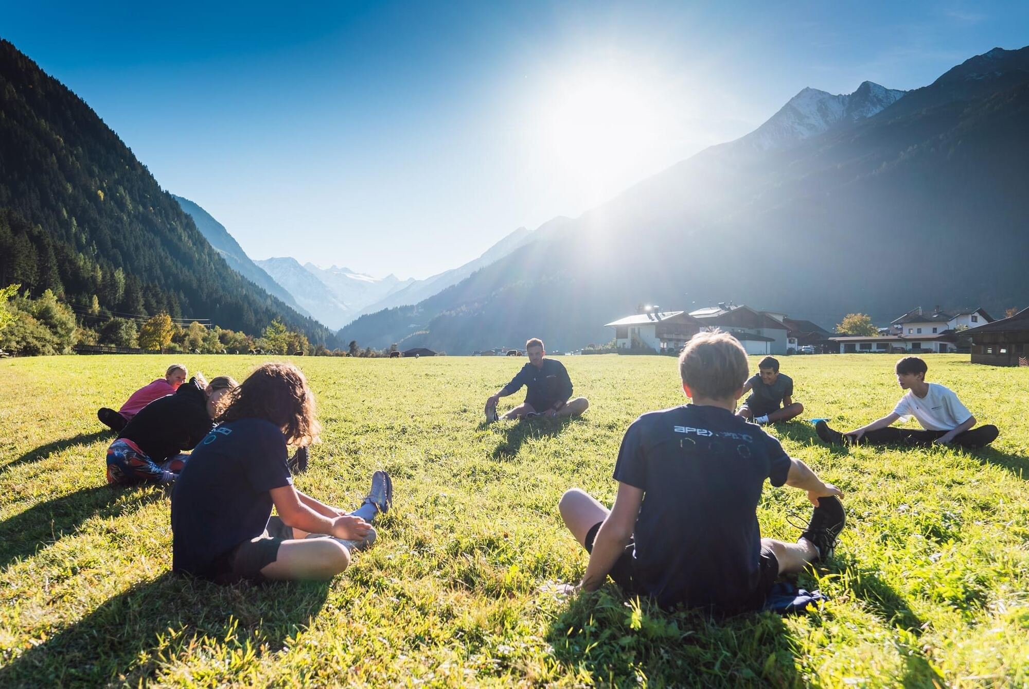Athletes sitting on an alpine meadow at sunset